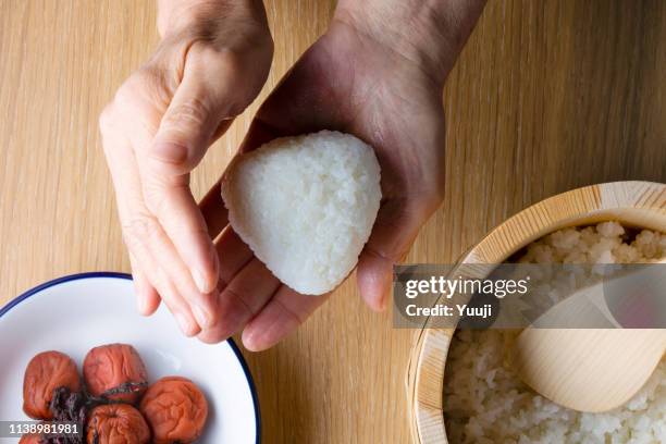 japanese senior woman holding rice ball and rice cooked with umeboshi - rice ball stock pictures, royalty-free photos & images