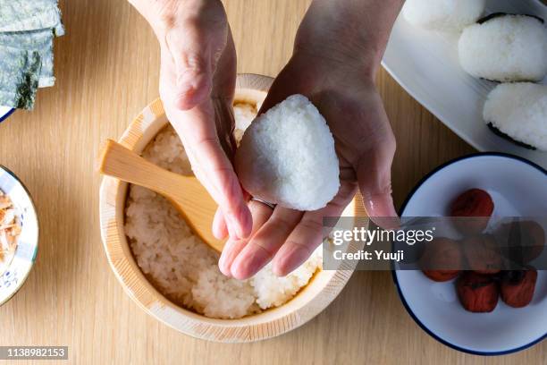senior japanese female hand holding a rice ball. ingredients are umeboshi, dried bonito and nori. - rice ball stock pictures, royalty-free photos & images