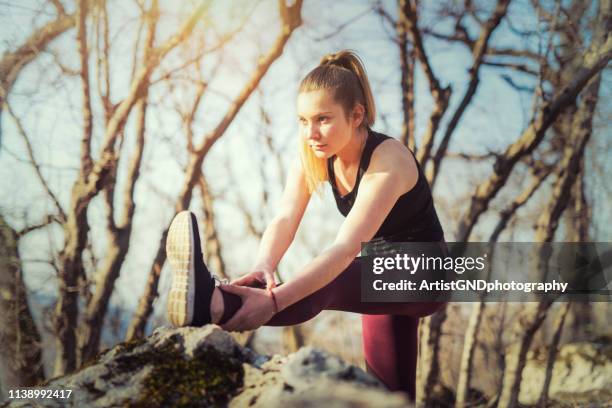 cross-country runner doing her warm-up on nature trail mountain - stretching hamstring stock pictures, royalty-free photos & images