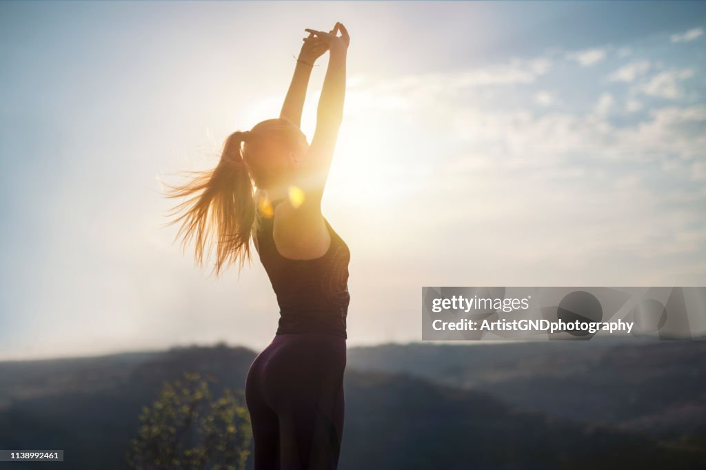 Liberté dans la nature, faire la gymnastique sur la lumière de coucher du soleil, préparation pour le jogging, s’étendant sur le coucher du soleil
