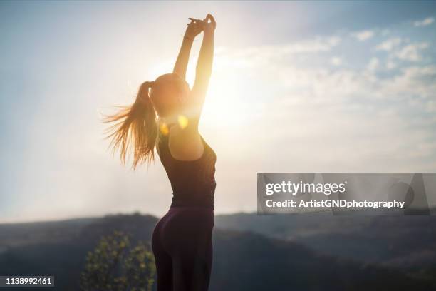 vrijheid in de natuur, gymnastiek doen op zonsondergang licht, voorbereiding voor joggen, stretching op zonsondergang - woman standing exercise stockfoto's en -beelden