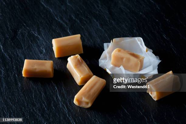 cream toffees and wrapping paper on black slate - dulce de azúcar y mantequilla fotografías e imágenes de stock