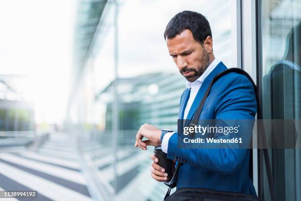 businessman with cup of coffee, looking on his watch - omlaag kijken stockfoto's en -beelden