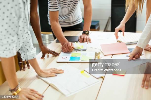 close-up of colleagues working together at desk in office discussing papers - organised group stock pictures, royalty-free photos & images