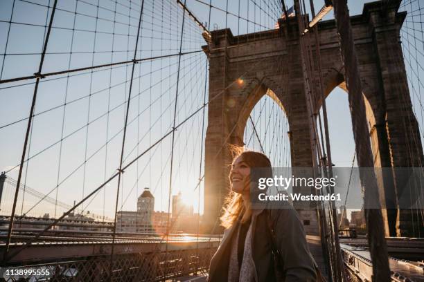 usa, new york, new york city, female tourist on brooklyn bridge at sunrise - brooklyn bridge stockfoto's en -beelden
