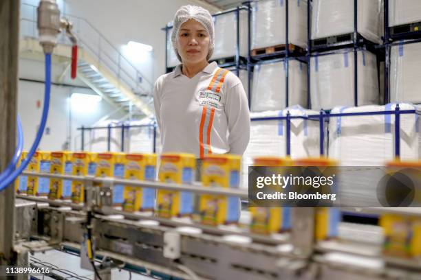 An employee monitors cartons of Chuckie, a Nestle SA chocolate flavored milk drink, moving along a conveyor at the company's factory in Batangas...