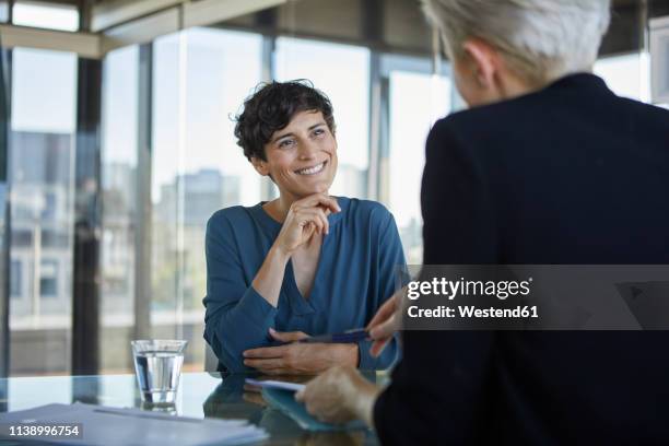 two businesswomen talking at desk in office - reden stock-fotos und bilder