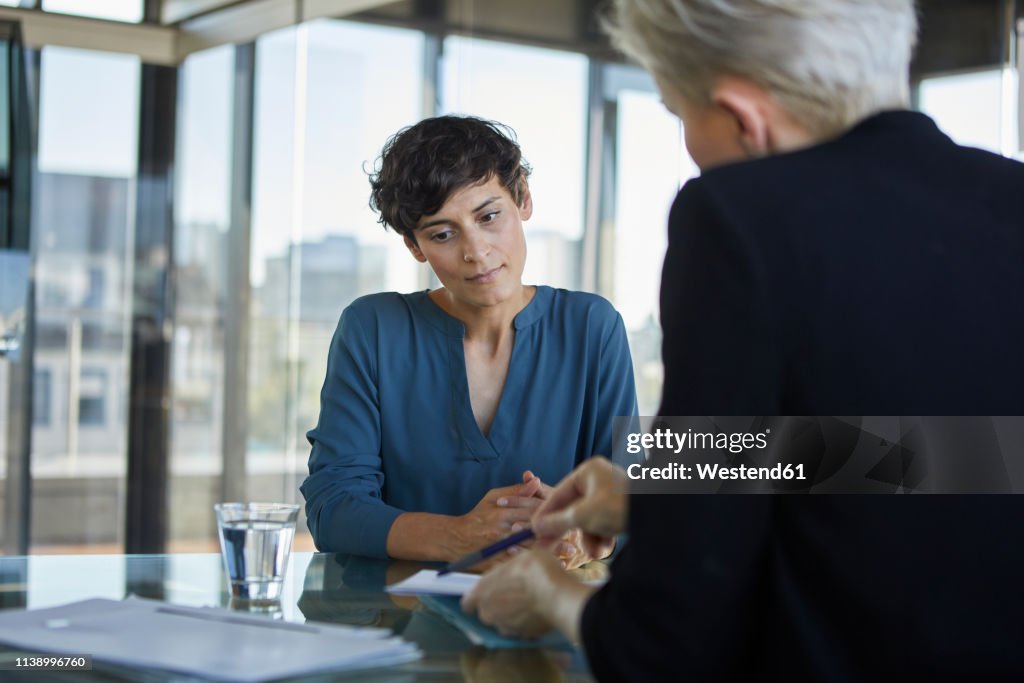 Two businesswomen talking at desk in office