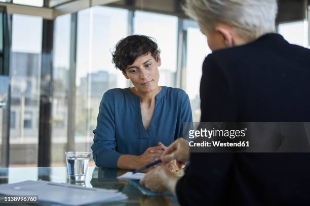 two businesswomen talking at desk in office - colloquio di lavoro foto e immagini stock