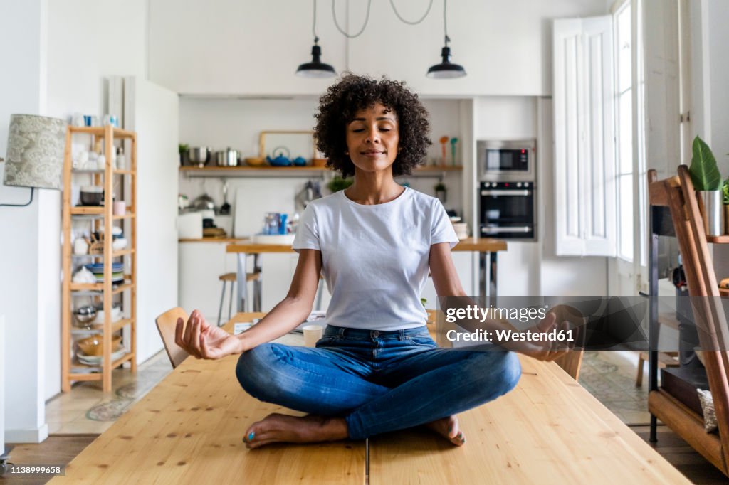 Smiling woman with closed eyes in yoga pose on table at home