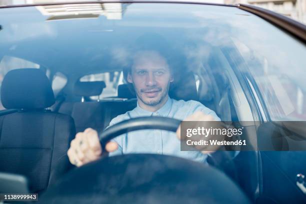 smiling businessman driving car - steering wheel stockfoto's en -beelden