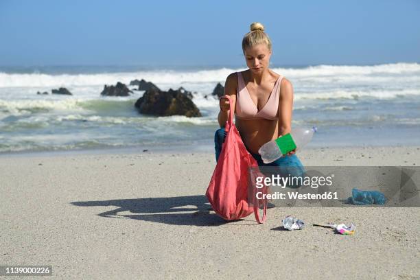 pregnant woman cleaning the beach from plastic waste - moment collection stockfoto's en -beelden