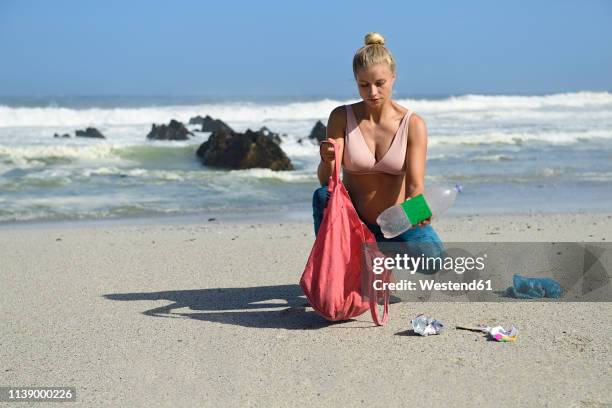 pregnant woman cleaning the beach from plastic waste - moment collection stock pictures, royalty-free photos & images