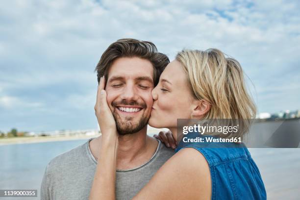 happy young couple kissing on the beach - young couples stock-fotos und bilder