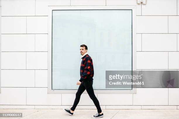 young man with casual clothes walking with a white wall and a large window in the background - hipster australia stock pictures, royalty-free photos & images