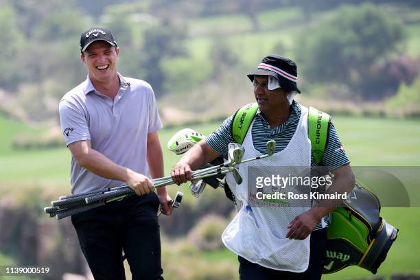 Callum Shinkwin on England assists his caddie by carrying clubs up the hill on the 17th during round two of the Hero Indian Open at the DLF Golf &...