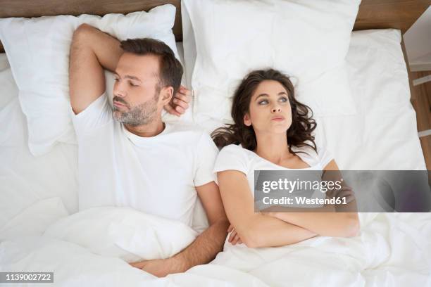 frustrated couple lying in bed - bed foto e immagini stock