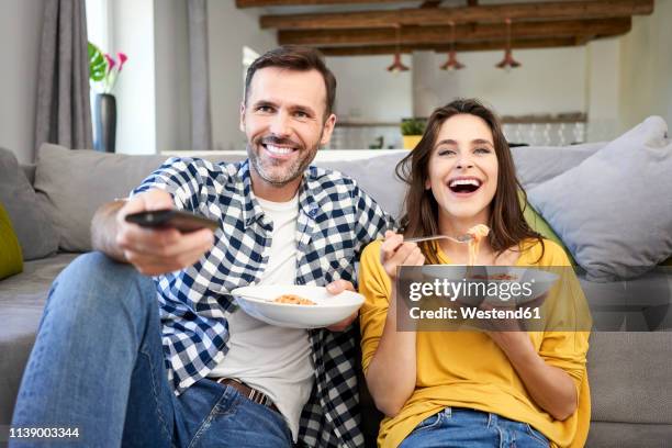 couple sitting in living room, eating spaghetti, watching tv - the joys of eating spaghetti stock pictures, royalty-free photos & images