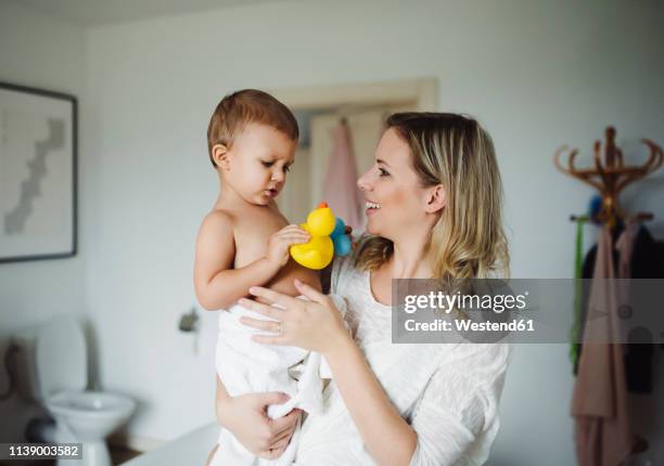 smiling mother holding toddler son in bathroom at home - rubber duck stock pictures, royalty-free photos & images