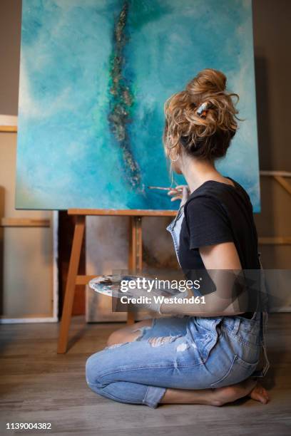 young woman painting in her atelier - palet stockfoto's en -beelden
