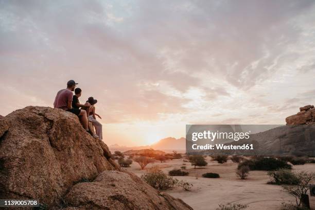 namibia, spitzkoppe, friends sitting on a rock watching the sunset - namibia women stock pictures, royalty-free photos & images