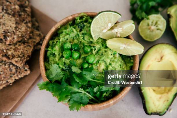 guacomole with peas, avocado, lime, coriander and crisp bread - guacamole stock pictures, royalty-free photos & images