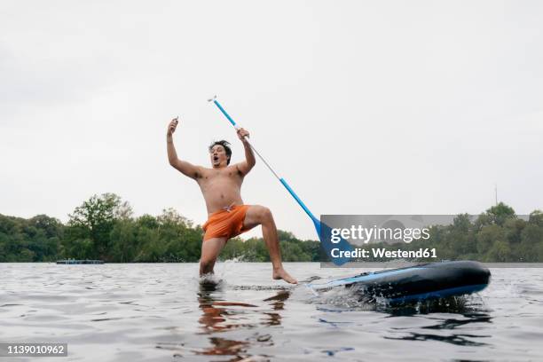 man falling from sup board while taking a selfie - careless ストックフォトと画像