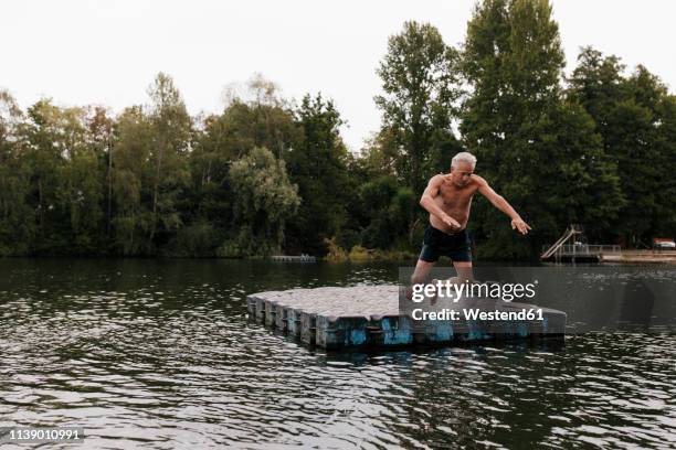 senior man jumping from raft in a lake - old people diving stock pictures, royalty-free photos & images