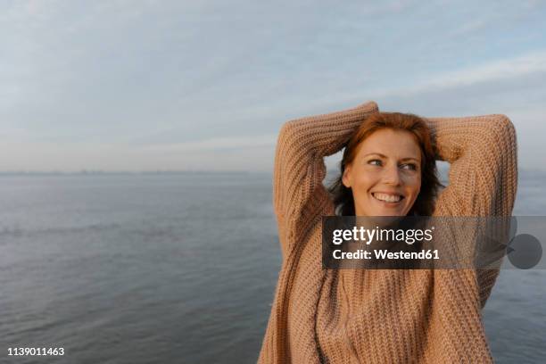 germany, hamburg, happy woman at the elbe shore - arms raised sunrise stock pictures, royalty-free photos & images