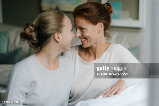 happy mother with teenage girl face to face on couch at home - girl with mother stock-fotos und bilder