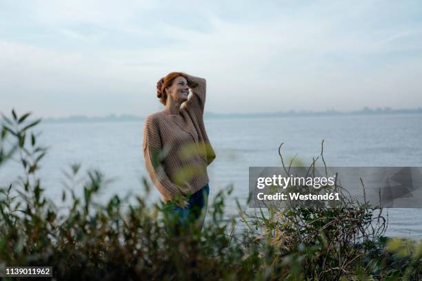 germany, hamburg, happy woman at the elbe shore - one embankment stock-fotos und bilder