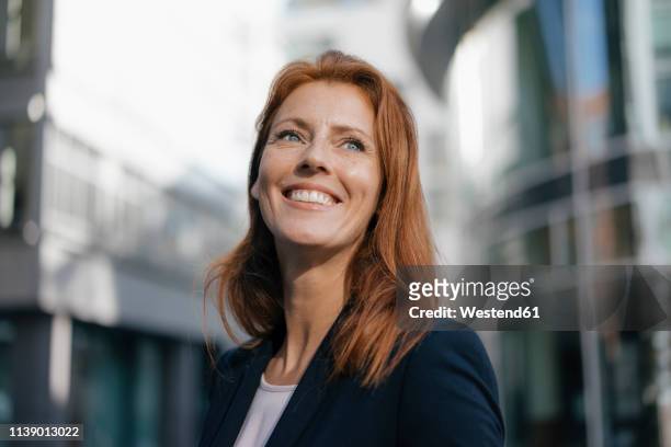 portrait of smiling businesswoman outdoors in the city - looking away stock-fotos und bilder