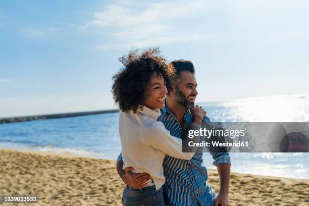 spain, barcelona, happy couple hugging on the beach - barcelona coast stock pictures, royalty-free photos & images