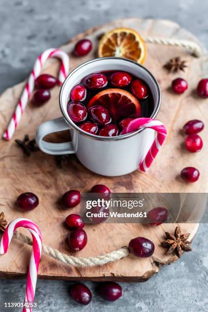 mug of mulled wine with cranberries, orange slice, star anise and candy cane - mulled wine stock pictures, royalty-free photos & images