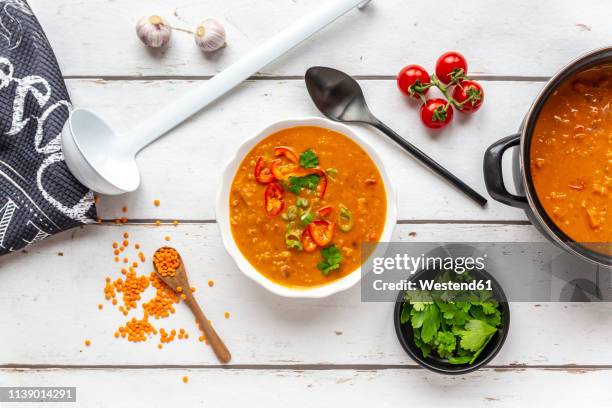 bowl and pot of garnished red lentil soup and ingredients on white wood - red lentil stock pictures, royalty-free photos & images