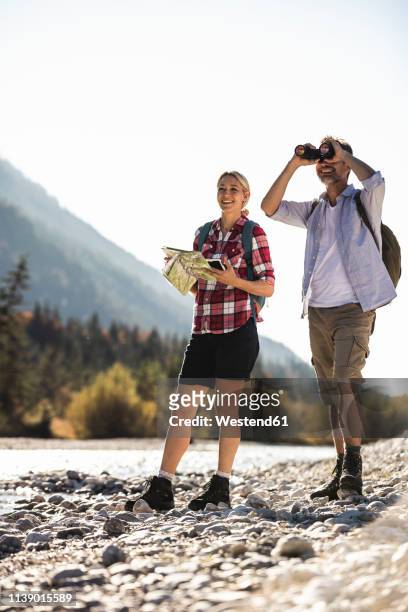 austria, alps, couple on a hiking trip with map and binoculars - österreich durchblick stock-fotos und bilder
