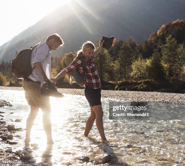 austria, alps, couple on a hiking trip wading in a brook - fun sommer berge stock-fotos und bilder