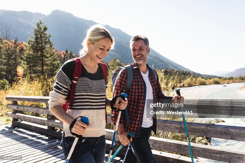 Austria, Alps, happy couple on a hiking trip crossing a bridge