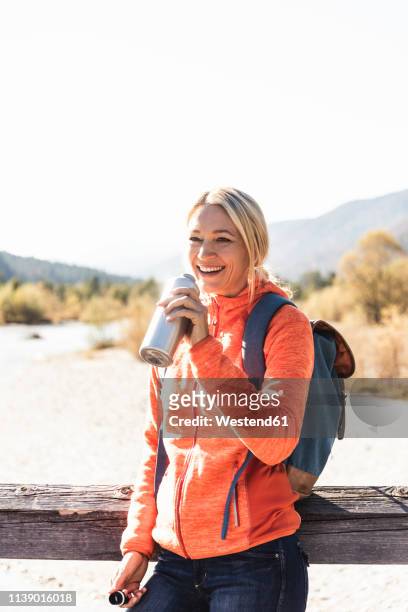 austria, alps, happy woman on a hiking trip drinking from bottle - portrait älter trinken stock-fotos und bilder