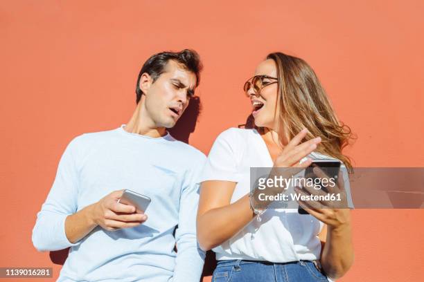 couple with cell phones outdoors on a sunny day - envy fotografías e imágenes de stock