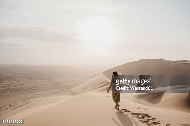 namibia, namib, back view of woman walking barefoot on desert dune - namibia women stock pictures, royalty-free photos & images