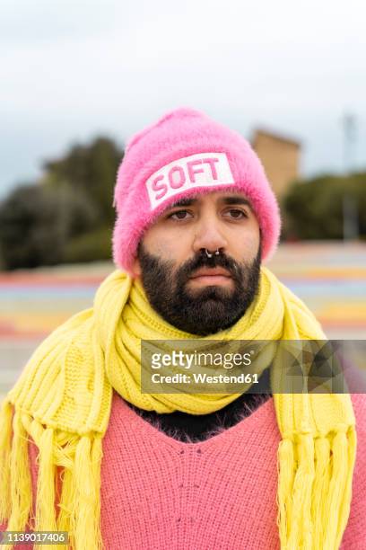 portrait of bearded gay with nose piercing wearing pink cap with the word 'soft' - mann pullover stock-fotos und bilder