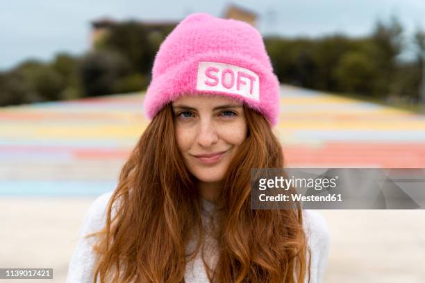 portrait of redheaded woman wearing pink cap with the word 'soft' - ironia imagens e fotografias de stock
