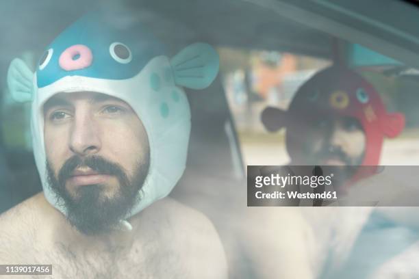 portrait of gay couple in a car wearing animal hats - animal friends stock-fotos und bilder