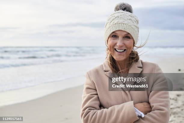 spain, menorca, portrait of happy senior woman on the beach in winter - bobble hat stock pictures, royalty-free photos & images
