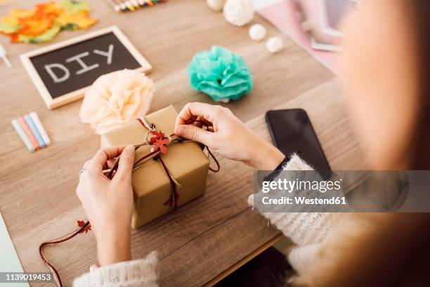 young woman wrapping a gift in her studio - luxury lounges stock pictures, royalty-free photos & images