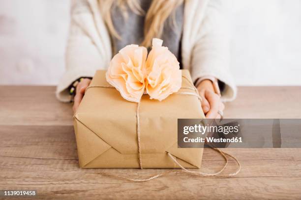 young woman showing a wrapped gift in her studio - luxury lounges stock pictures, royalty-free photos & images