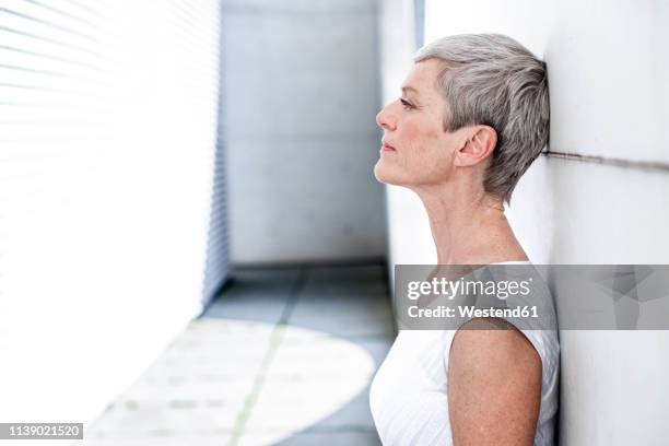 profile of pensive mature businesswoman leaning against wall - lentigo stock pictures, royalty-free photos & images