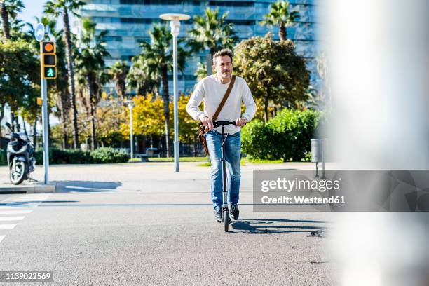 mature man commuting in the city, using kick scooter on the pavemnet - man on scooter stock pictures, royalty-free photos & images