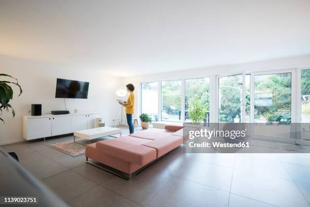 woman using laptop in a spacious living room at home - design laptop woman stock-fotos und bilder